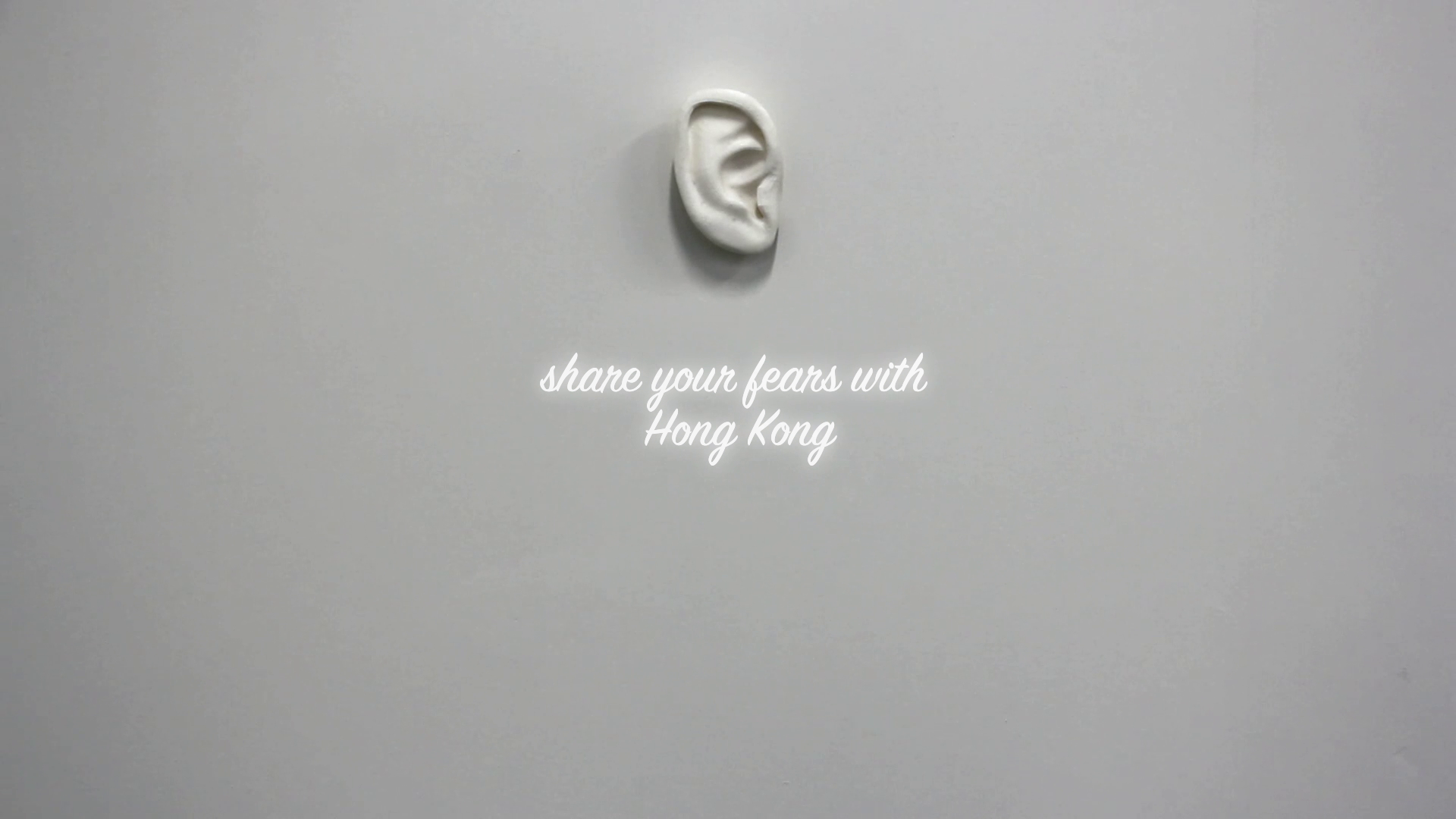 Sculptural ear on a wall with the text 'share your fears with Hong Kong'