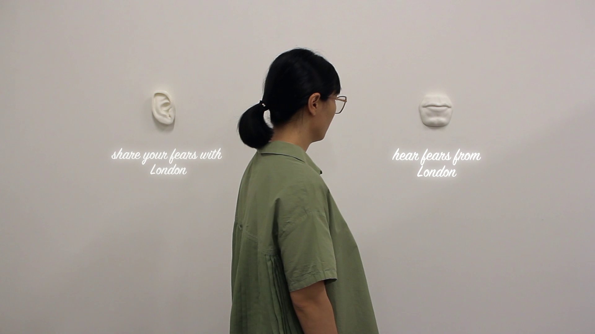 Visitor between the ear and mouth sculptures of Fear Exchange