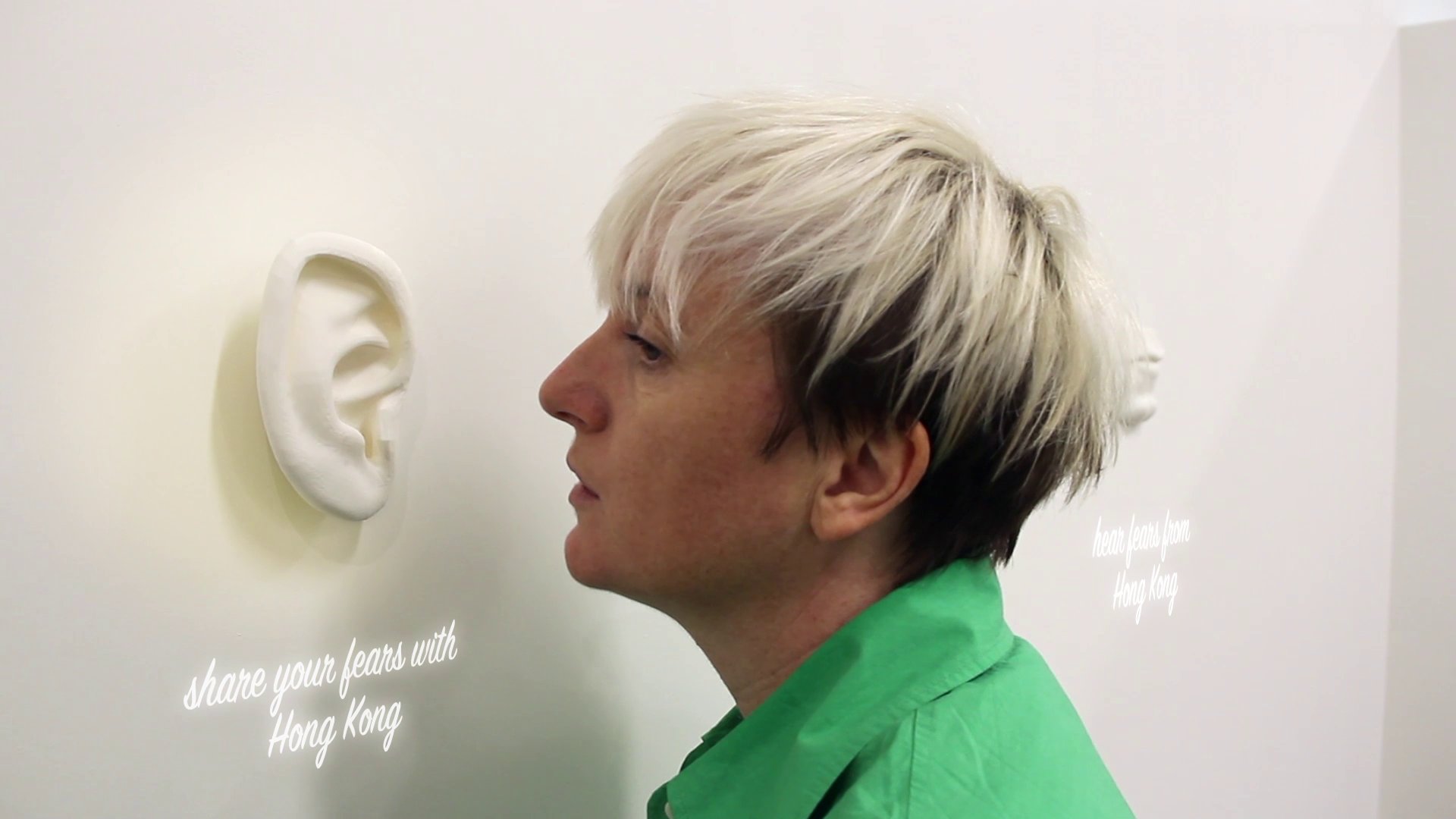 Visitor beside the sculptural ear with the text 'share your fears with Hong Kong'